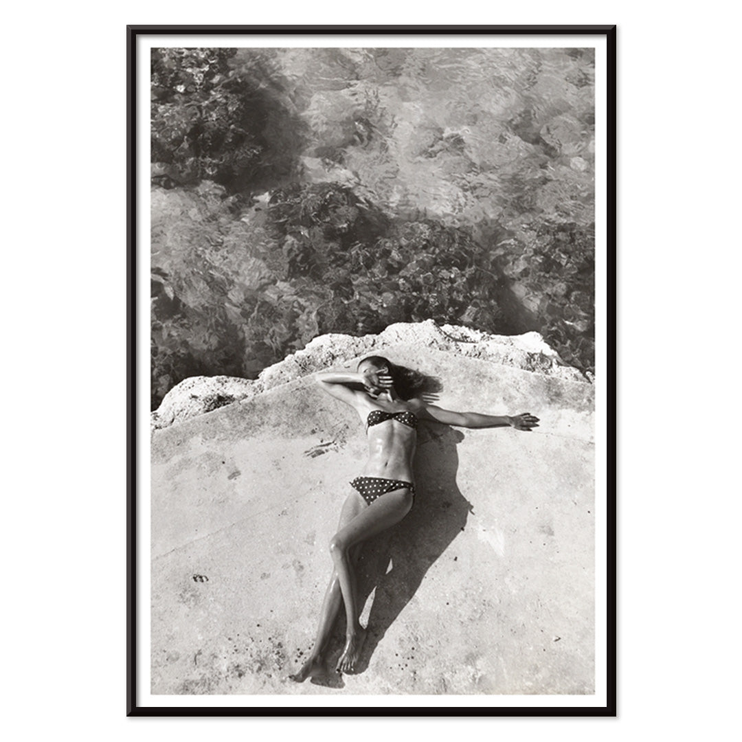 Woman in bikini lying on platform near water in Montego Bay Jamaica artwork by Nickerson Paine poster, with black aluminium frame on white background
