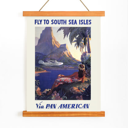 Vintage travel poster of a woman in a floral dress on a tropical island with a Pan American seaplane by Paul George Lawler, with wooden magnetic frame on white background