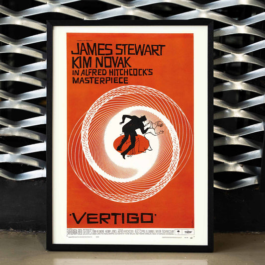 Vertigo movie poster by Saul Bass featuring vibrant orange background swirling spiral and silhouetted figures graphic design, framed and displayed in home decor