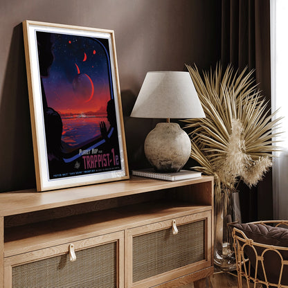 Colorful sci fi poster of TRAPPIST-1e by NASA showing vibrant alien landscape with planets glowing sky and silhouetted figures viewed from a window, framed and displayed in home decor